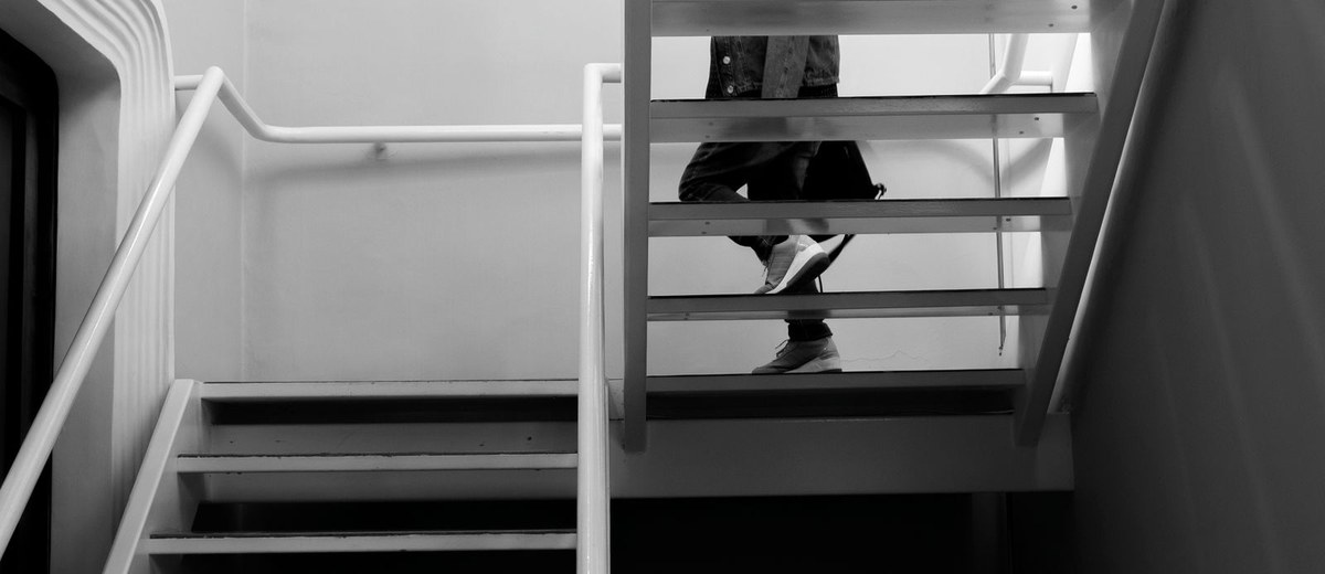 Mulher descendo escada em prédio moderno, em preto e branco